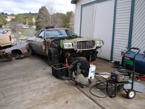 1973 Ford Ranchero - The front end of a 1973 Ford Ranchero is disassembled and supported by jack stands in a driveway.
