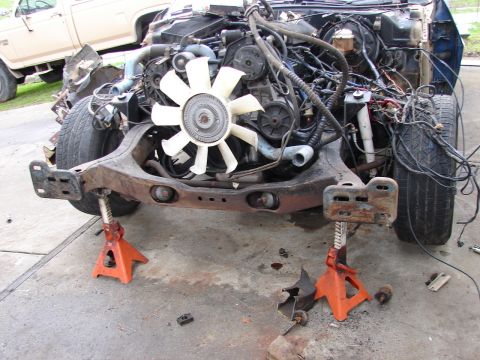 1973 Ford Ranchero - The front end of a vehicle, including the engine and chassis, is supported by jack stands. Another vehicle is visible in the background.
