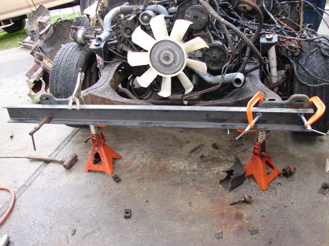 1973 Ford Ranchero - A vehicle's front clip removed exposing the V8 engine with a white plastic clutch fan, belts and pulleys, while a steel crossmember is clam…