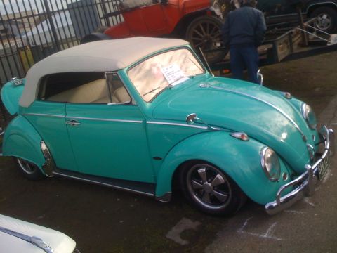 1983 Ford Bronco - A teal convertible Volkswagen Beetle is parked outdoors with other vehicles in the background.