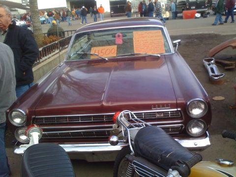 1983 Ford Bronco - A maroon sedan, possibly a 1965 Mercury Comet, is for sale next to a motorcycle.