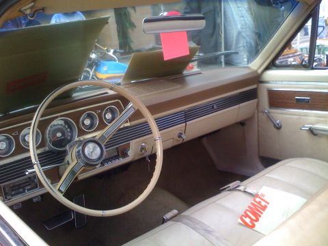 1983 Ford Bronco - The interior of a 1967 Mercury Comet features a beige steering wheel and dashboard with woodgrain accents.