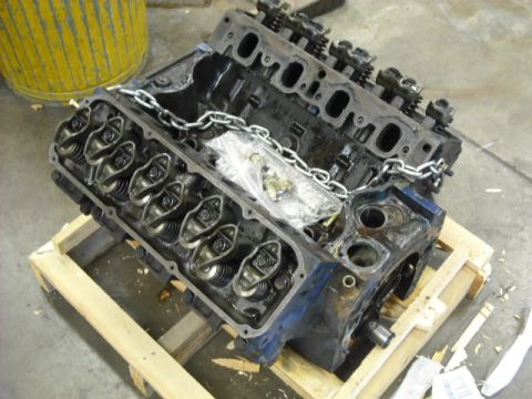 1979 Ford Bronco - An engine block, likely a V8, is secured with a chain and rests on a wooden pallet, ready for transport or repair.