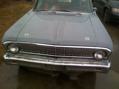 1983 Ford Bronco - Front view of a gray car with a chrome grille and bumper, showing a glimpse of its red interior.