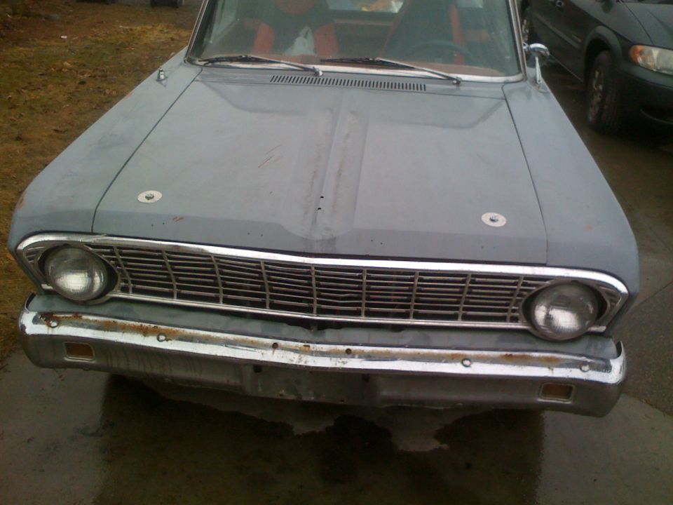 Gray car front with chrome grille and bumper, red interior visible