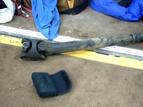 1995 Ford Bronco - A driveshaft and a small black case are shown on a carpeted floor.