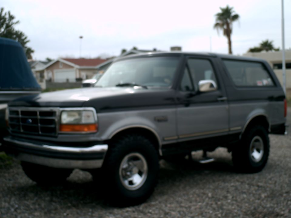 1994 Ford Bronco, black and silver, 3/4 front view, parked on gravel.