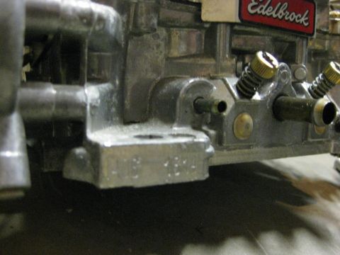 1979 Ford Bronco - A close-up, angled view shows the side of a silver Edelbrock carburetor with visible brass screws and springs. The carburetor is mounted on…