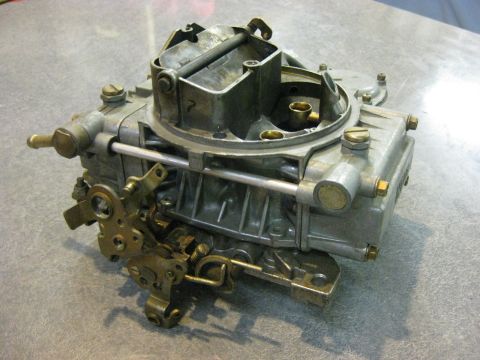1979 Ford Bronco - A close-up, high-angle view of a vintage carburetor, likely for a classic Ford Bronco, is shown resting on a textured gray surface.