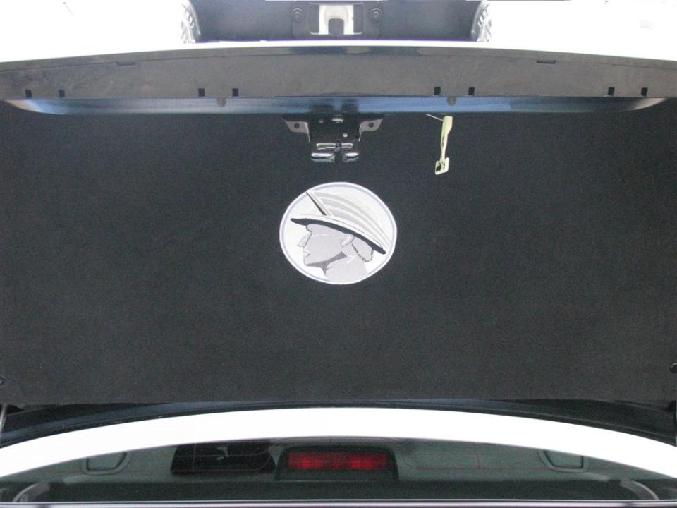 Carpeted trunk lid liner with embroidered Mercury god-head emblem on a black sedan