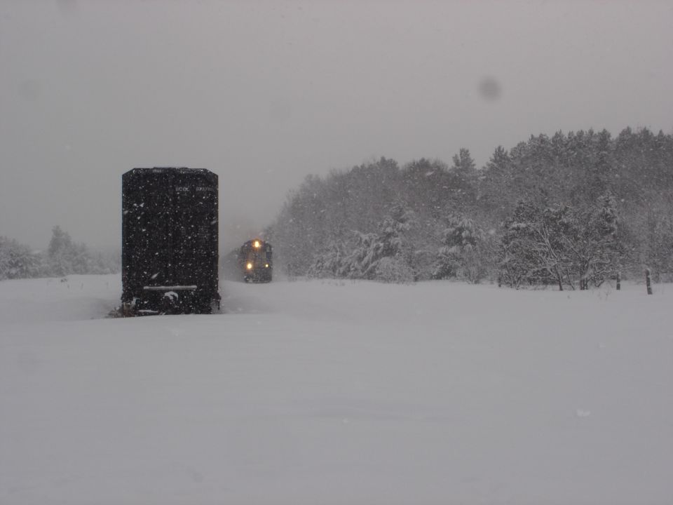 Train moving through a snowy landscape during a blizzard.
