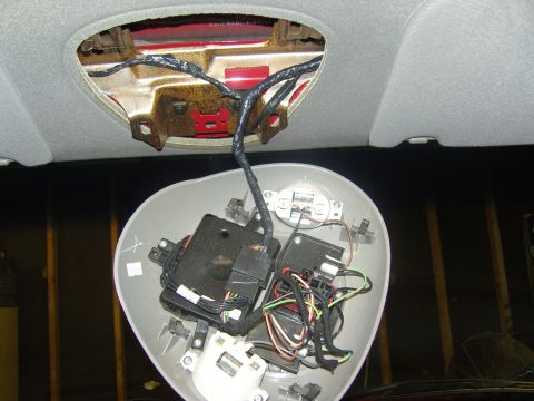 2007 Ford Mustang - Photograph of a removed overhead console showing internal wiring harness and actuator motors, not a technical document.