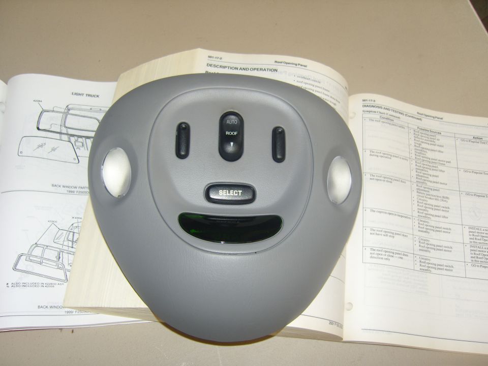 Photo of a gray overhead console shell with open service manual behind it