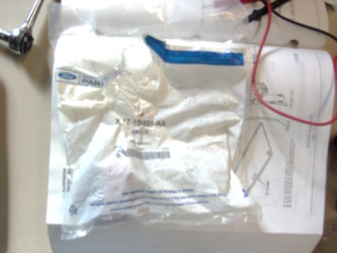 2007 Ford Mustang - Photograph of a bagged Ford service part and switch resting on a service manual, not a document page itself.