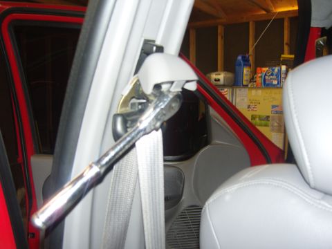 2007 Ford Mustang - Photograph of a truck B-pillar and seat belt with a ratchet held against the trim, not a document.