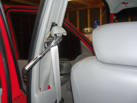 2007 Ford Mustang - Photograph of a gray B-pillar and seat belt anchor with a chrome ratchet, not a document.