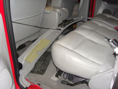 2007 Ford Mustang - Photograph of the gray leather rear bench seat and floor of a red truck, not a document.