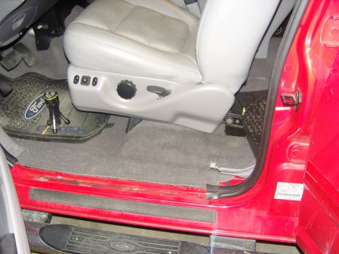 2007 Ford Mustang - Photograph of a truck power seat switch, door sill and Ford floor mat, not a document.