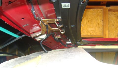 2007 Ford Mustang - Photograph of the painted A-pillar and cowl structure of a red truck under a removed headliner, not a document.