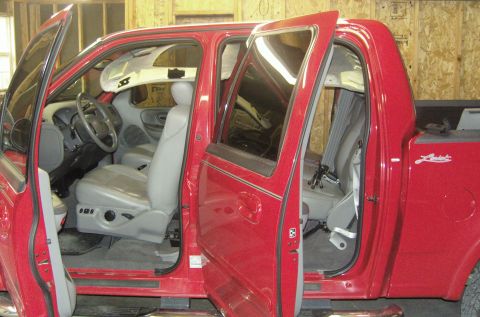 2007 Ford Mustang - Photograph of a red Ford extended-cab pickup with doors open showing the gray interior, not a document.