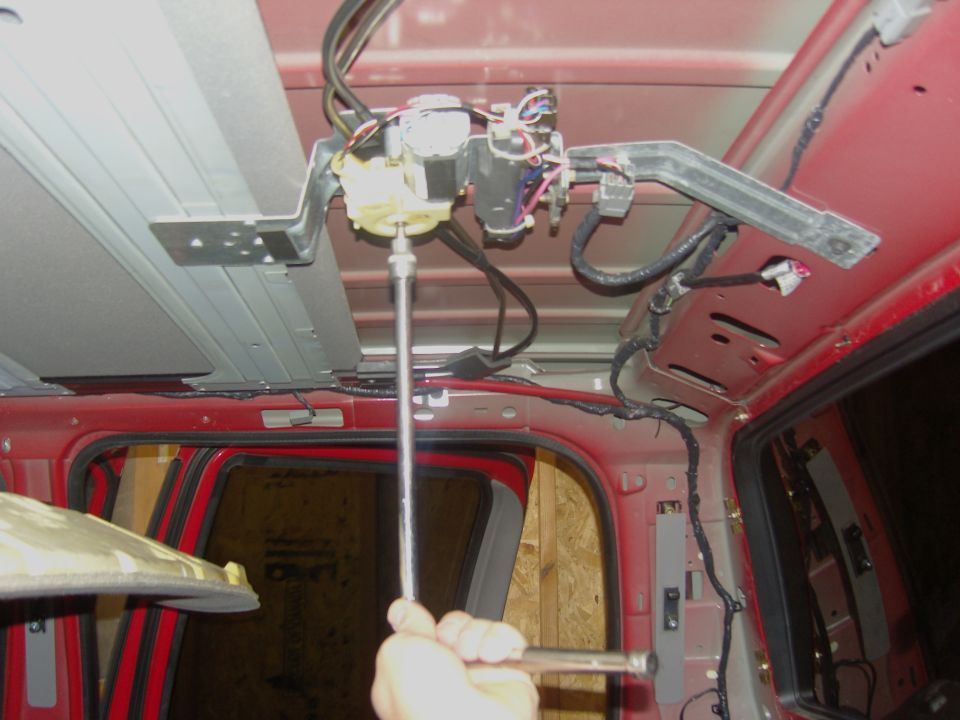 Photo of a hand using a screwdriver on an overhead console mechanism