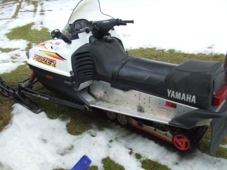 1996 Ford Bronco - A white Yamaha snowmobile with a black seat is parked on grass with patches of snow. The snowmobile has "Phazer" written on the front fairi…