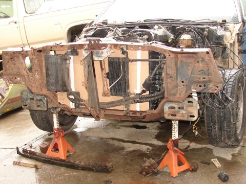 1973 Ford Ranchero - Front-end teardown of a vehicle down to bare frame horns, showing the radiator support, radiator and oil cooler, steering rack and rusty fr…