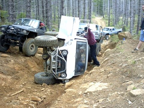 1995 Ford Bronco - Multiple off-road vehicles navigate a challenging trail, with one vehicle overturned.