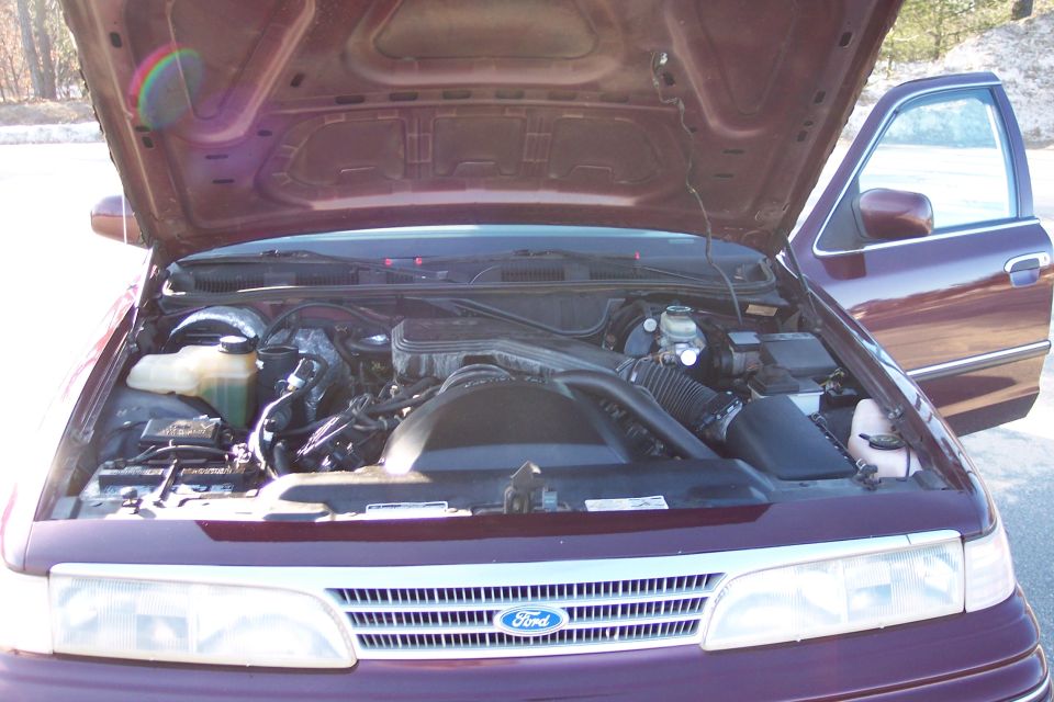 2001 Ford Crown Victoria engine bay with hood open and driver's door ajar.