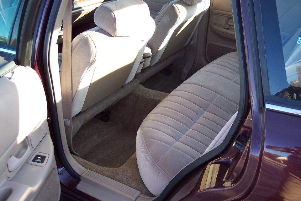 Interior of a dark red sedan, showing tan ribbed rear and front seats.