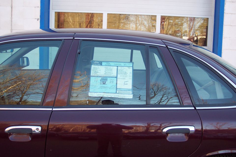 2001 Ford Crown Victoria sedan, dark red, side view, with window sticker on rear passenger window.