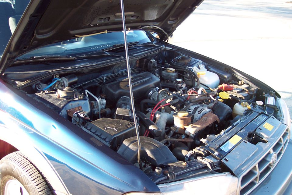 Engine bay of a dark blue vehicle, hood open.