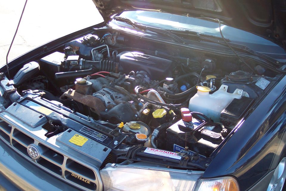 Engine bay of a dark blue Subaru Outback with the hood open.