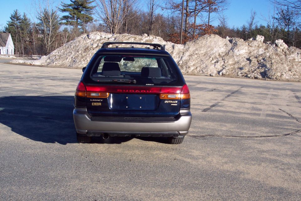 Rear view of a dark blue Subaru Outback station wagon with 'LEGACY EXETER' and 'OUTBACK AWD' badges.