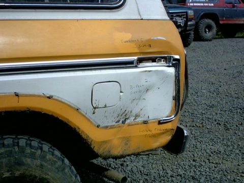 1995 Ford Bronco - Mud-splattered rear quarter panel of a vintage Ford Bronco with handwritten inscriptions and another Bronco in the background.