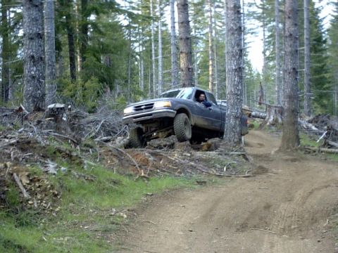 1995 Ford Bronco - A Ford Ranger navigates a challenging off-road trail in a wooded area.