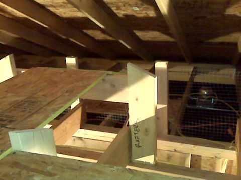 2005 Ford Mustang - This is a construction scene inside an attic with wooden rafters and plywood sheeting. A piece of wood has "RAFTER" written on it.