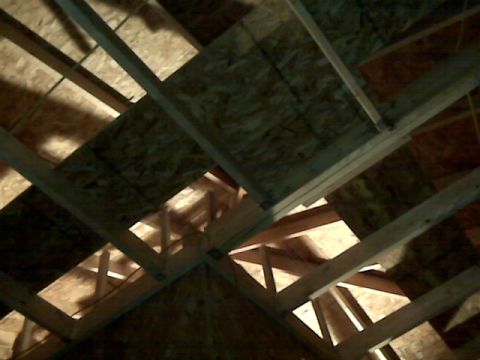 2005 Ford Mustang - This image shows the interior framing of a roof structure. Wooden beams and plywood sheeting are visible, with light filtering through gaps…
