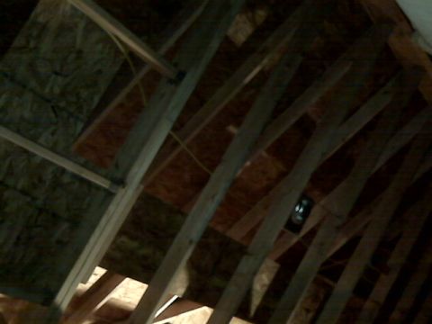 2005 Ford Mustang - This is a low-angle, close-up shot of the interior framing of a building's attic. Wooden beams and plywood sheeting are visible, along with…