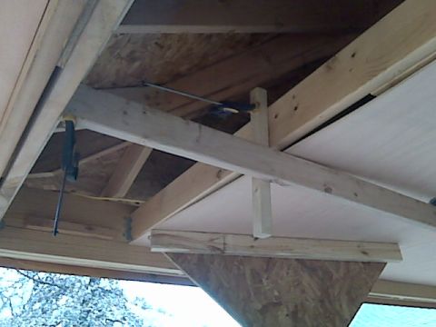2005 Ford Mustang - This is an image of construction framing and plywood, likely part of a roof or ceiling structure. There are wooden beams, braces, and clamp…