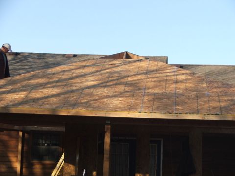 2005 Ford Mustang - A construction worker wearing a white baseball cap stands on a roof covered with plywood under a clear blue sky. The roof is part of a hous…
