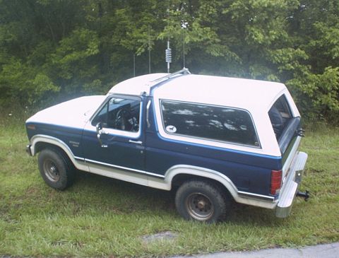 1986 Ford Bronco - This 1986 Ford Bronco is parked on a grassy area with trees behind it.