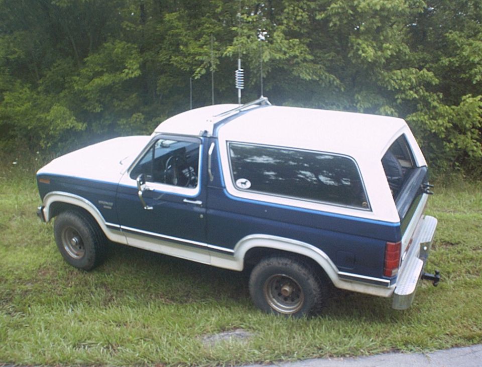 1986 Ford Bronco parked on grass with trees in background