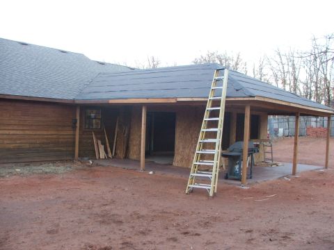 2005 Ford Mustang - A construction scene shows a house with a new roof being installed, a ladder leaning against the structure, and a grill on the patio.