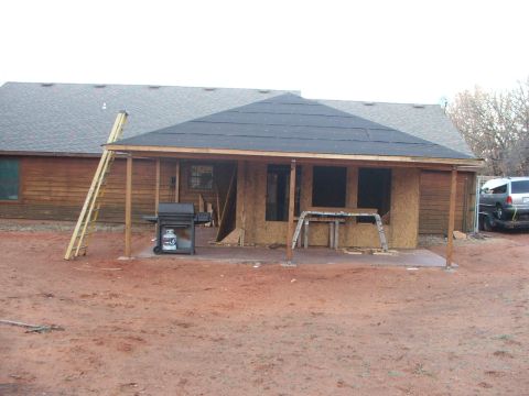 2005 Ford Mustang - A silver SUV is parked on a trailer in front of a house under construction. The house has a wooden exterior and a new roof is being install…