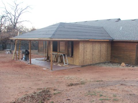 2005 Ford Mustang - A covered patio area is under construction next to a house with wooden siding. A grill and ladder are visible on the patio.