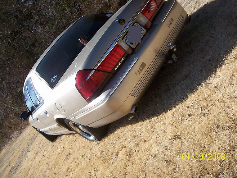 Overhead rear-quarter view of a tan Mercury sedan on a dirt drive