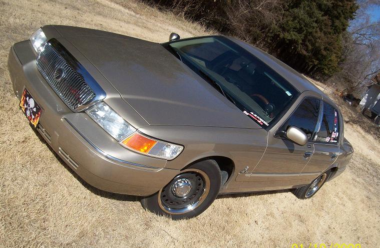 Front three-quarter high-angle view of a tan Mercury Grand Marquis in a field