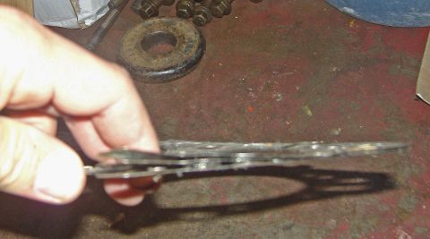 2007 Ford Mustang - Photograph of a hand holding stacked metal shims or clutch plates above a workbench, not a document.