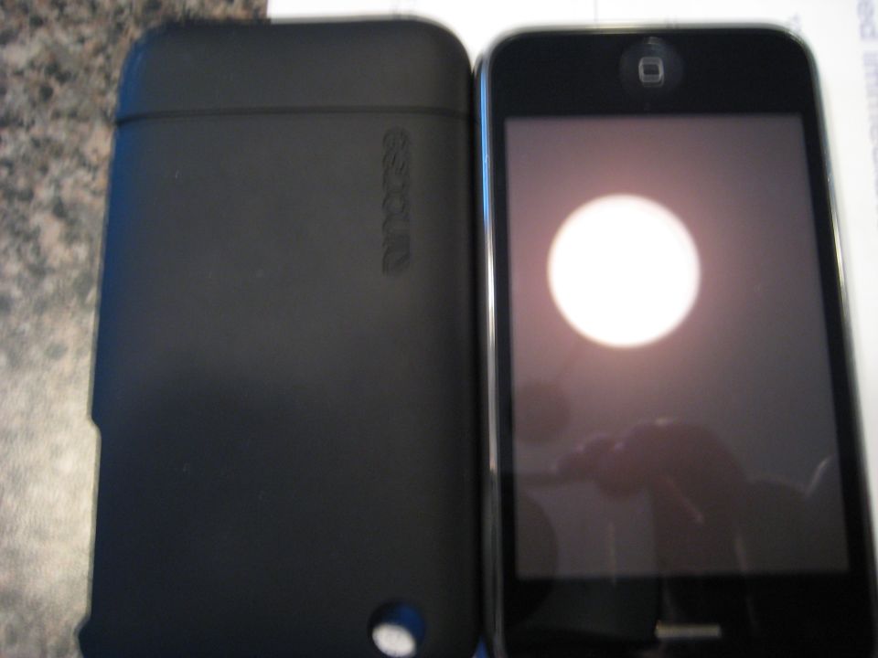 Black Incase phone case next to a smartphone with a bright circle on the screen.